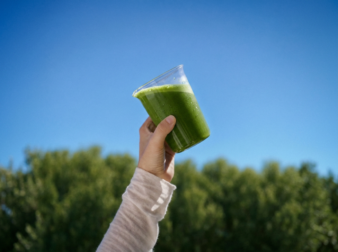 Moringa drink raised against a blue sky